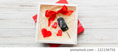 Black car key in a present box with a ribbon and red heart on colored background. Valentine day composition Top view Black car key in a present box with a ribbon and red heart on colored background. Valentine day composition Top view 122136758