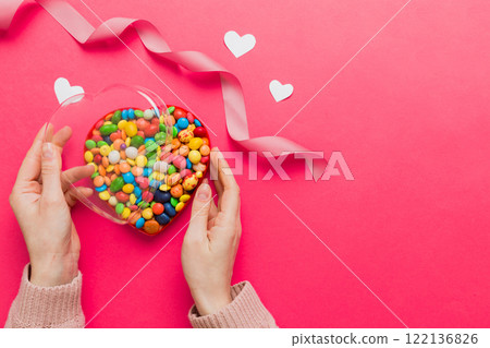 Female hands with delicious candies in box on color background 122136826