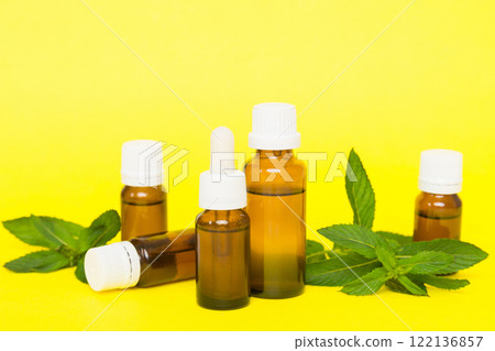 Natural Mint Essential Oil in a Glass Bottle. organic cosmetics with herbal extracts of mint on colored background 122136857