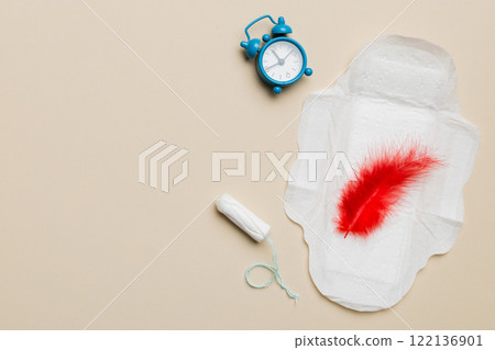 Ringing alarm clock with sanitary female tampons and menstrual sanitary pads. Medical concept of woman critical days and menstruation. Female daily hygiene. Copy space 122136901