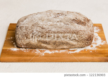 Freshly baked bread on cutting board against white wooden background. perspective view bread with copy space 122136903