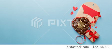 Envelope on colored background for Valentine Day with gift box and chocolate. Heart shaped with gift box of chocolates top view with copy space 122136909