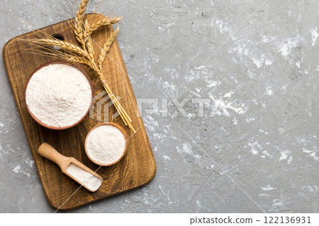 Flat lay of Wheat flour in wooden bowl with wheat spikelets on colored background. world wheat crisis 122136931