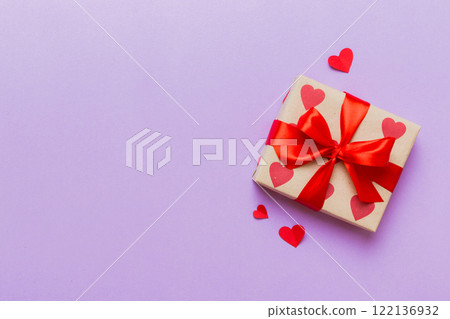 Top view photo of valentine day decorations gift box with red ribbon bow on colored background. Holiday gift boxes with top view 122136932