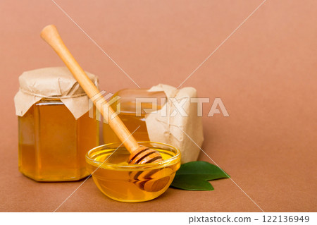 Honey in jar with leaves and honey dipper on colored background top view with copy text Honey in jar with leaves and honey dipper on colored background top view with copy text 122136949