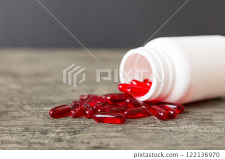 Red pills spilled around a pill bottle. Medicines and prescription pills flat lay background. Red medical capsules 122136970
