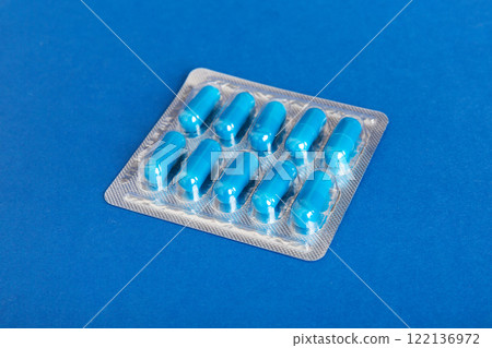 Blister package with Vitamin on color background. Medicine pills on a light background. Medicines and prescription pills flat lay background. blue medical tablets in blister Blister package with Vitamin on color background. Medicine pills on a light background. Medicines and prescription pills flat lay background. blue medical tablets in blister 122136972