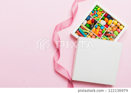Set of different sweet candy in a paper box with a satin ribbon on a colored background. Holiday concept Set of different sweet candy in a paper box with a satin ribbon on a colored background. Holiday concept 122136974