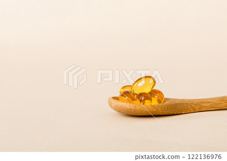 Vitamin omega capsules in a spoon on a colored background. Pills served as a healthy meal. Red soft gel vitamin supplement capsules on spoon Vitamin omega capsules in a spoon on a colored background. Pills served as a healthy meal. Red soft gel vitamin supplement capsules on spoon 122136976