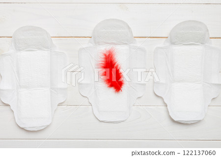 Women hygiene products or Sanitary pad with red feather on colored background. Pastel color. Closeup. Empty place for text. Female daily hygiene 122137060