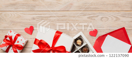Envelope on colored background for Valentine Day with gift box and chocolate. Heart shaped with gift box of chocolates top view with copy space Envelope on colored background for Valentine Day with gift box and chocolate. Heart shaped with gift box of chocolates top view with copy space 122137090
