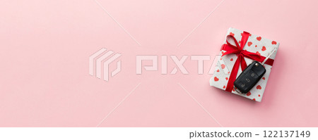 Car key on paper gift box with red ribbon bow and heart on table background. Holidays present top view concept Car key on paper gift box with red ribbon bow and heart on table background. Holidays present top view concept 122137149