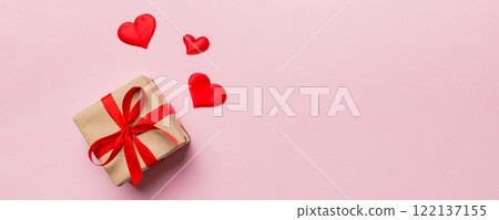 Valentine day composition: red gift box with bow and heart. Christmas present. View from above. Space for text. Holday greeting card Valentine day composition: red gift box with bow and heart. Christmas present. View from above. Space for text. Holday greeting card 122137155