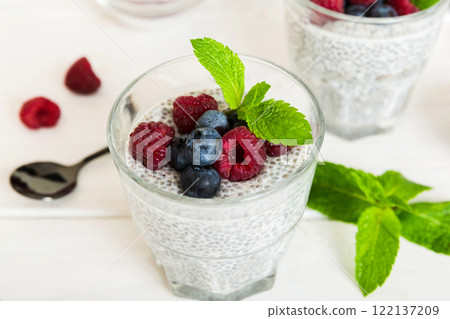 Healthy breakfast or morning with chia seeds vanilla pudding raspberry and blueberry berries on table background, vegetarian food, diet and health concept. Chia pudding with raspberry and blueberry 122137209