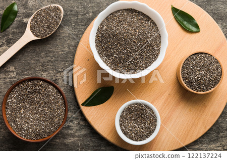 Chia seeds in bowl and spoon on colored background. Healthy Salvia hispanica in small bowl. Healthy superfood Chia seeds in bowl and spoon on colored background. Healthy Salvia hispanica in small bowl. Healthy superfood 122137224