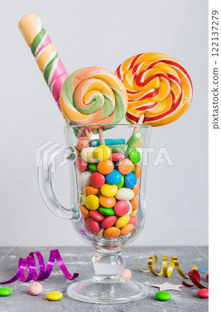 Colorful candies in cup on table on light background background. Large swirled lollipops. Creative concept of a jar full of delicious sweets from the candy store 122137279