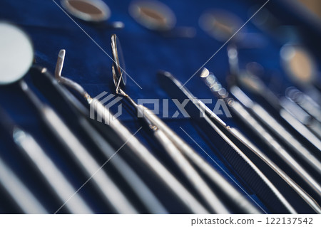 row of various basic dental tools on display on blue background with shallow depth of field row of various basic dental tools on display on blue background with shallow depth of field 122137542