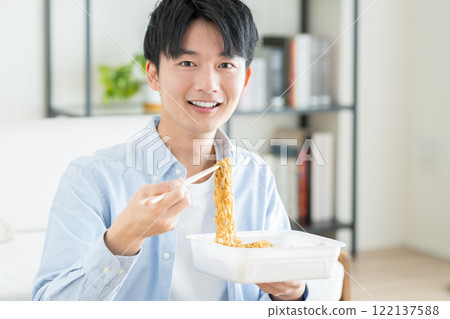 A young man eating instant yakisoba 122137588