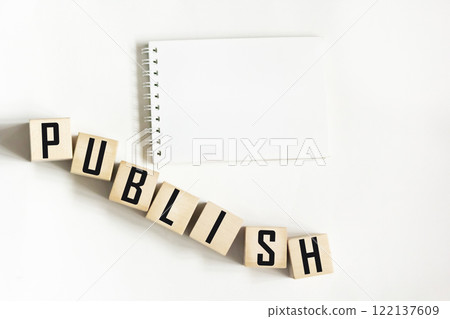 A white notebook on a white background. The word "PUBLISH" is written on wooden blocks A white notebook on a white background. The word "PUBLISH" is written on wooden blocks 122137609