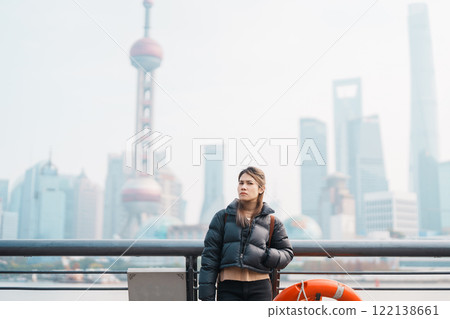 woman traveler visiting in Shanghai, China. Female Tourist with backpack sightseeing Shanghai view of Lujiazui in The Bund of Shanghai. landmark and popular for tourism attractions. Vacation concept 122138661