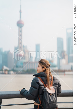 woman traveler visiting in Shanghai, China. Female Tourist with backpack sightseeing Shanghai view of Lujiazui in The Bund of Shanghai. landmark and popular for tourism attractions. Vacation concept 122138665
