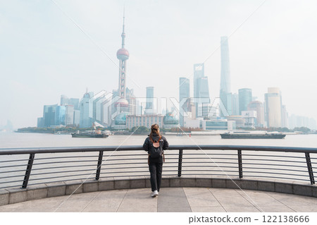woman traveler visiting in Shanghai, China. Female Tourist with backpack sightseeing Shanghai view of Lujiazui in The Bund of Shanghai. landmark and popular for tourism attractions. Vacation concept woman traveler visiting in Shanghai, China. Female Tourist with backpack sightseeing Shanghai view of Lujiazui in The Bund of Shanghai. landmark and popular for tourism attractions. Vacation concept 122138666
