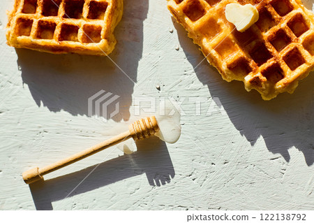 Delicious waffles topped with a touch of honey on a bright background in the morning light Delicious waffles topped with a touch of honey on a bright background in the morning light 122138792