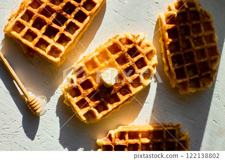Delicious waffles topped with a touch of honey on a bright background in the morning light Delicious waffles topped with a touch of honey on a bright background in the morning light 122138802