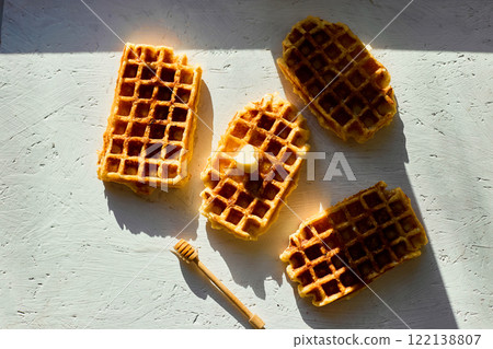 Delicious waffles topped with a touch of honey on a bright background in the morning light Delicious waffles topped with a touch of honey on a bright background in the morning light 122138807