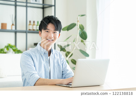 在客廳裡使用電腦的年輕人 122138818