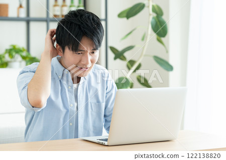 Young man using a computer in the living room Young man using a computer in the living room 122138820