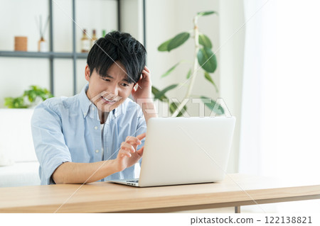 Young man using a computer in the living room Young man using a computer in the living room 122138821