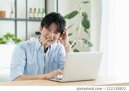 Young man using a computer in the living room Young man using a computer in the living room 122138822