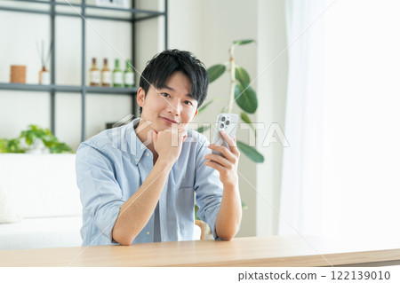 年輕人在客廳看智慧型手機 122139010