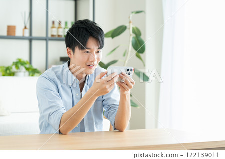 年輕人在客廳看智慧型手機 年輕人在客廳看智慧型手機 122139011