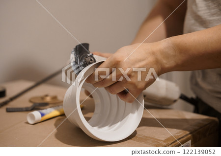 A Craftsman Assembling a White Component with Tools on a Workbench 122139052