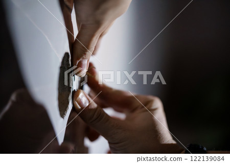 Close-up of Hands Removing a Sticker from a Surface 122139084