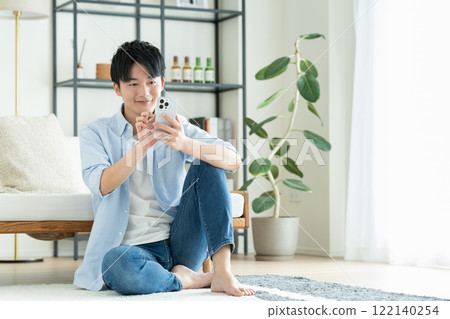 年輕人在客廳看智慧型手機 122140254