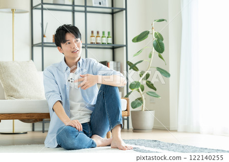 A young man looking at his smartphone in the living room 122140255