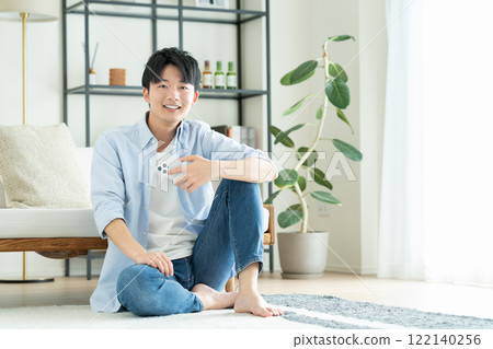 A young man looking at his smartphone in the living room 122140256