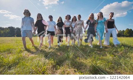 High school students walking hand in hand through a summer field 122142064