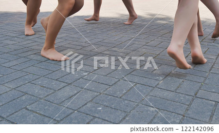 Ballet dancers stroll barefoot on a cobblestone street, savoring the end of the school year after a rehearsal Ballet dancers stroll barefoot on a cobblestone street, savoring the end of the school year after a rehearsal 122142096