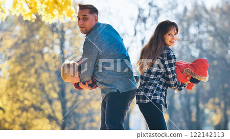 Family playing happily amid golden autumn foliage, parents spending precious moments with young kids in sunlit park landscape Family playing happily amid golden autumn foliage, parents spending precious moments with young kids in sunlit park landscape 122142113