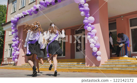 Three happy young women with purple ribbons happily leaving school building on their final day, excited for summer break and the freedom ahead Three happy young women with purple ribbons happily leaving school building on their final day, excited for summer break and the freedom ahead 122142172