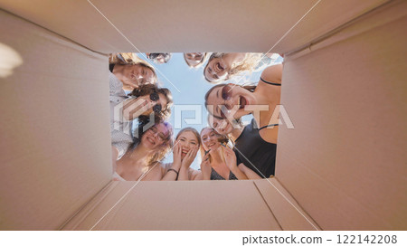 Excited high school girls express surprise and happiness while looking inside a cardboard box during their summer break 122142208