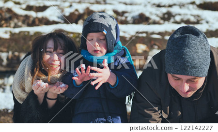 Happy family enjoying playful moments in the snow, basking in the warmth of a sunny winter day filled with laughter and joy 122142227