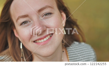 Smiling auburn haired woman with warm brown eyes radiating joy and infectious positiveness in close up portrait Smiling auburn haired woman with warm brown eyes radiating joy and infectious positiveness in close up portrait 122142255