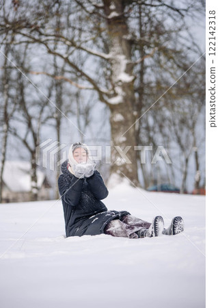 Schoolgirl having fun in a winter park, creating snow magic on a snowy day 122142318