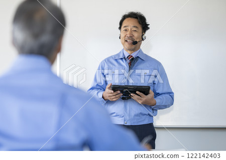 一位身穿工作服的資深工程師拿著平板電腦並講話，技術研討會圖像 122142403