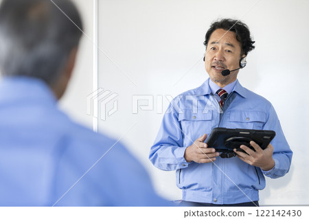 Veteran technician in work clothes talking with tablet, technical seminar image 122142430